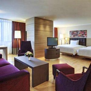 Spacious twin room with beds, desk, TV screen and sofa at the Hilton Mainz.