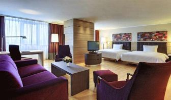 Spacious twin room with beds, desk, TV screen and sofa at the Hilton Mainz.