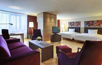 Spacious twin room with beds, desk, TV screen and sofa at the Hilton Mainz.