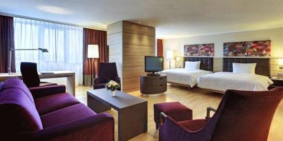 Spacious twin room with beds, desk, TV screen and sofa at the Hilton Mainz.