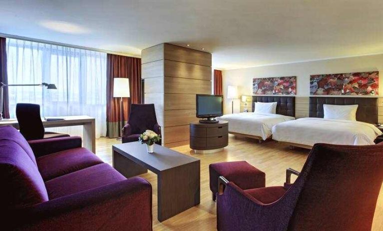 Spacious twin room with beds, desk, TV screen and sofa at the Hilton Mainz.