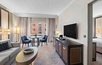 Spacious living room with working station by the window at the Hilton Munich City.