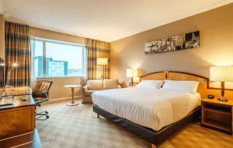 King bedroom with soafa and desk at the Hilton Paris Charles de Gaulle Airport.