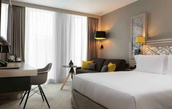 King bedroom with desk and sofa at the Hilton Garden Inn Bordeaux Centre.