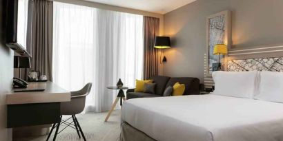 King bedroom with desk and sofa at the Hilton Garden Inn Bordeaux Centre.