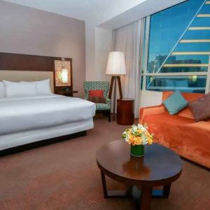 King bedroom with window and sofa at the Hilton Dallas Plano Granite Park.