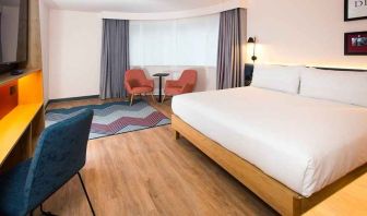 cosy king room with TV, desk, and lounge area ideal for working remotely at Hampton by Hilton London Park Royal.