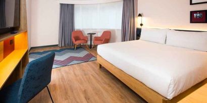 cosy king room with TV, desk, and lounge area ideal for working remotely at Hampton by Hilton London Park Royal.