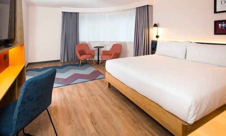 cosy king room with TV, desk, and lounge area ideal for working remotely at Hampton by Hilton London Park Royal.