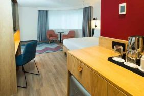 spacious king room with work desk, lounge area, TV, and coffeee stand at Hampton by Hilton London Park Royal.