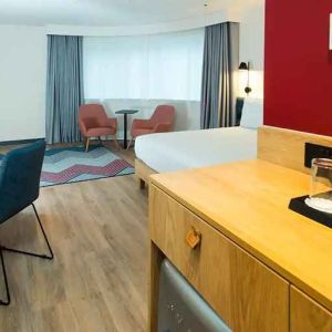 spacious king room with work desk, lounge area, TV, and coffeee stand at Hampton by Hilton London Park Royal.