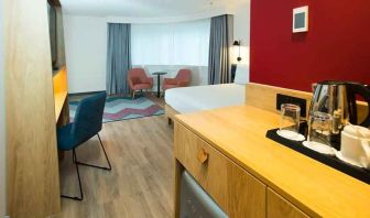 spacious king room with work desk, lounge area, TV, and coffeee stand at Hampton by Hilton London Park Royal.