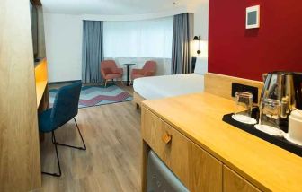 spacious king room with work desk, lounge area, TV, and coffeee stand at Hampton by Hilton London Park Royal.