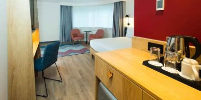 spacious king room with work desk, lounge area, TV, and coffeee stand at Hampton by Hilton London Park Royal.