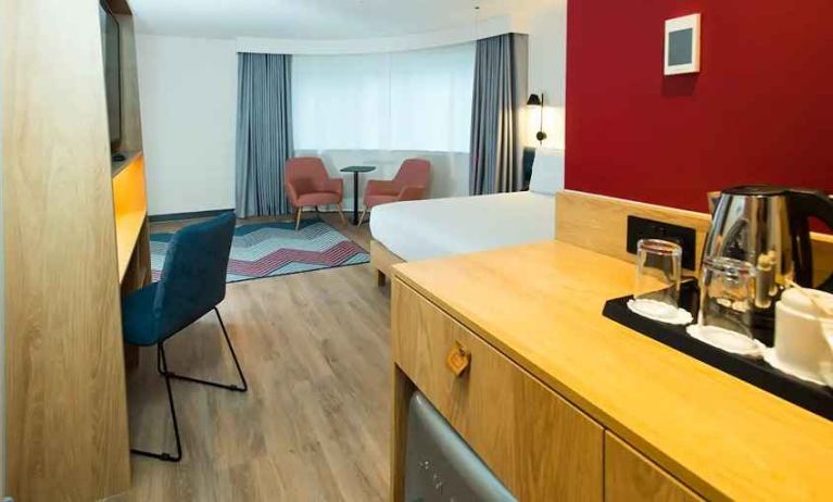 spacious king room with work desk, lounge area, TV, and coffeee stand at Hampton by Hilton London Park Royal.