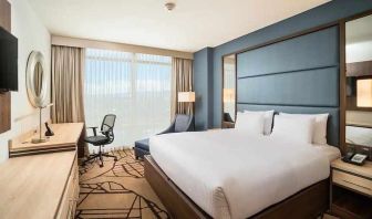 comfortable king room with TV, work desk, and natural light at Hilton Garden Inn Bogota Airport.