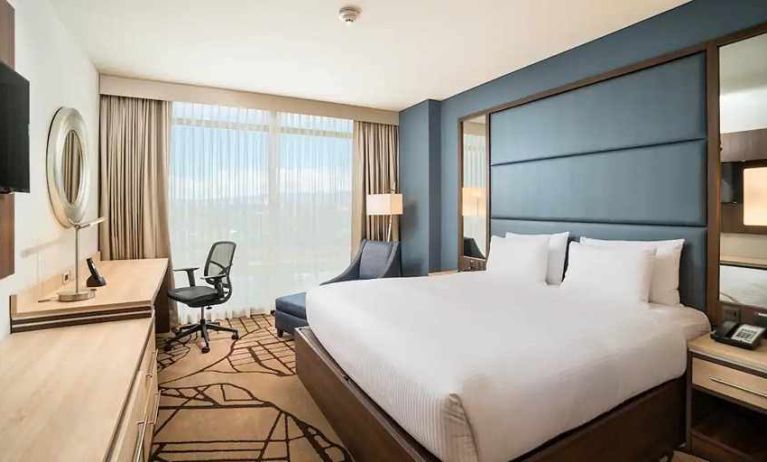 comfortable king room with TV, work desk, and natural light at Hilton Garden Inn Bogota Airport.