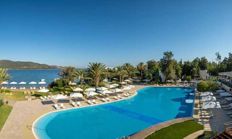 stunning outdoor pool surrounded by sun beds and pool umbrellas at DoubleTree by Hilton Bodrum Isil Club Resort.