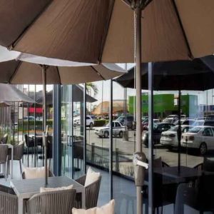 Outdoor terrace with chairs, tables and sun umbrellas at the Hampton Inn by Hilton Cancun Cumbres.