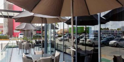 Outdoor terrace with chairs, tables and sun umbrellas at the Hampton Inn by Hilton Cancun Cumbres.