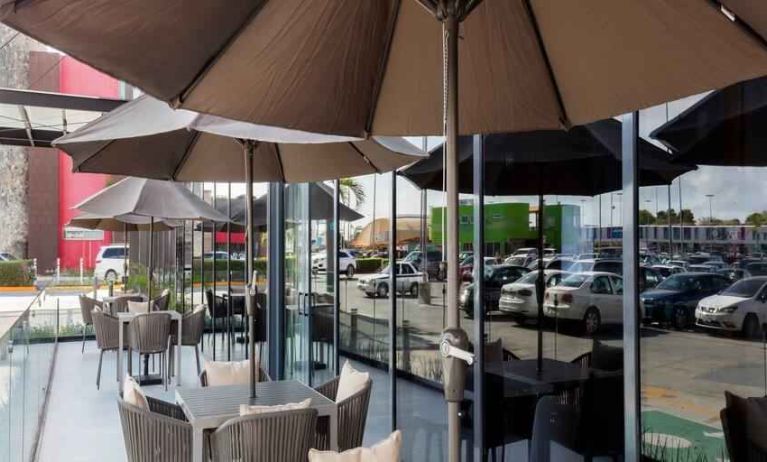 Outdoor terrace with chairs, tables and sun umbrellas at the Hampton Inn by Hilton Cancun Cumbres.