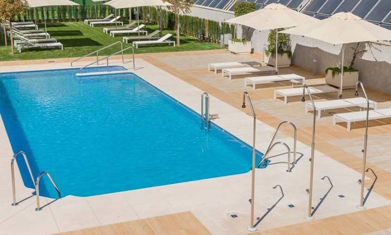 stunning outdoor pool with sun beds and umbrellas at Hilton Garden Inn Sevilla.