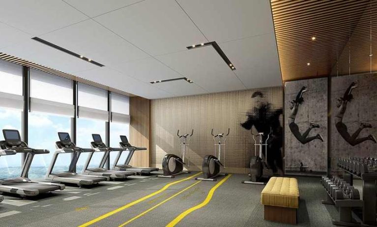 well equipped fitness center with lots of natural light at DoubleTree by Hilton Kunming Airport.