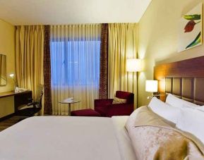 comfortable delux king room with TV, desk, chair, and couch at Hilton Garden Inn Kutahya.