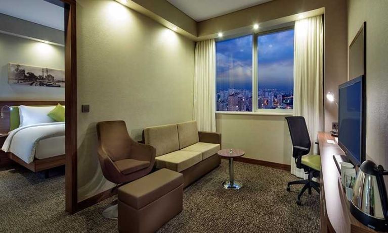 spacious king suite with TV, work desk and chair, lounge area, and coffee station at Hampton by Hilton Istanbul Kayasehir.