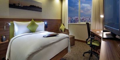 comfortable king bedroom with TV, desk, and chair at Hampton by Hilton Istanbul Kayasehir.