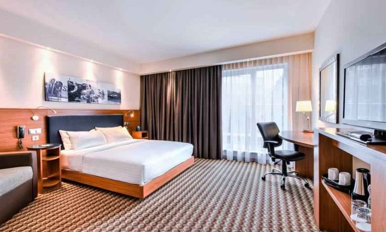 King guestroom with desk, sofa and TV screen at the Hampton by Hilton Warsaw Airport.