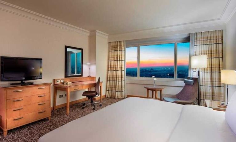 lovely king bedroom with TV, desk, and chair at Adana HiltonSA.