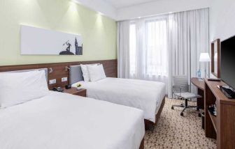 Twin room with TV screen and working station at the Hampton by Hilton Gdansk Oliwa.