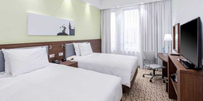 Twin room with TV screen and working station at the Hampton by Hilton Gdansk Oliwa.