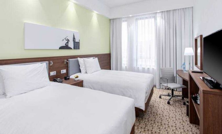 Twin room with TV screen and working station at the Hampton by Hilton Gdansk Oliwa.