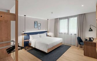 standard king room with chair, desk and TV at Hilton Garden Inn Bucharest Airport.