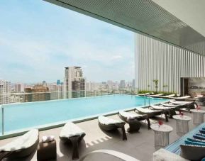Beautiful outdoor pool with lounges overlooking the city at the Hilton Sukhumvit Bangkok.