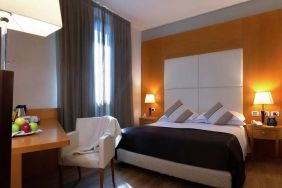 comfortable king suite with table, chair, and TV at Hilton Garden Inn Milan Malpensa.