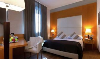 comfortable king suite with table, chair, and TV at Hilton Garden Inn Milan Malpensa.