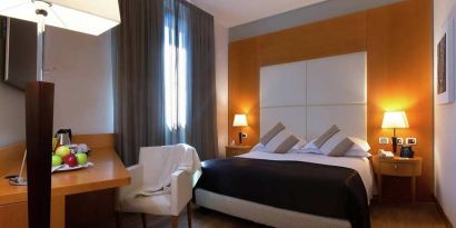 comfortable king suite with table, chair, and TV at Hilton Garden Inn Milan Malpensa.