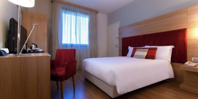 delux king room with TV, desk, and chair at Hilton Garden Inn Milan Malpensa.