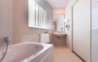 clean and spcious bathroom with bath and shower at Hilton Garden Inn Milan Malpensa.