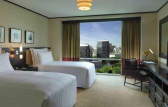 Twin room with TV screen and desk at the Conrad Bangkok.