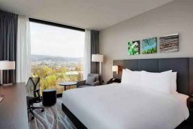 Bright king bedroom with desk along the window at the Hilton Garden Inn Zurich Limmattal.