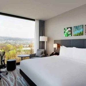 Bright king bedroom with desk along the window at the Hilton Garden Inn Zurich Limmattal.