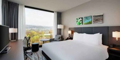 Bright king bedroom with desk along the window at the Hilton Garden Inn Zurich Limmattal.