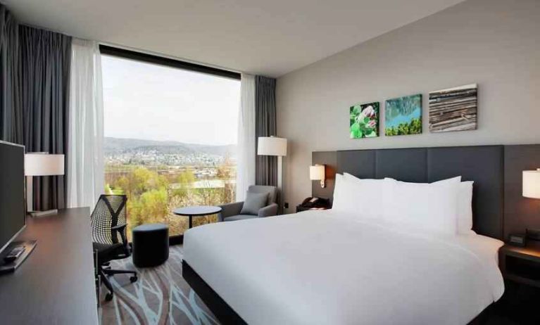 Bright king bedroom with desk along the window at the Hilton Garden Inn Zurich Limmattal.