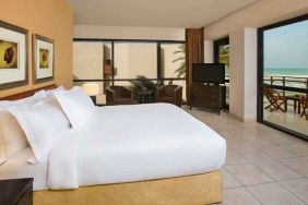 spacious king room with TV, lounge chairs, and terrace at Hilton Kuwait Resort.