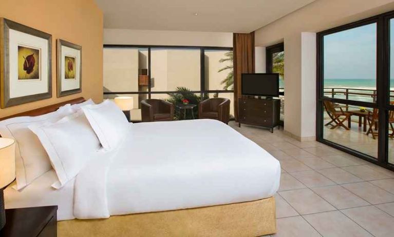 spacious king room with TV, lounge chairs, and terrace at Hilton Kuwait Resort.