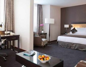 spacious king room with TV, work desk, chair, and couch at DoubleTree by Hilton Luxembourg.